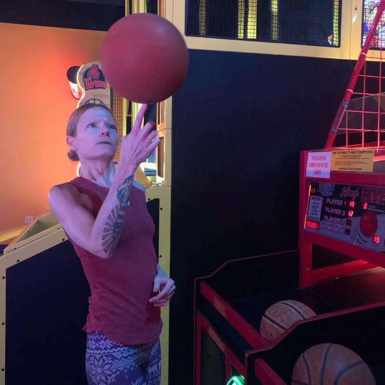 Woman spinning a basketball at an arcade game
